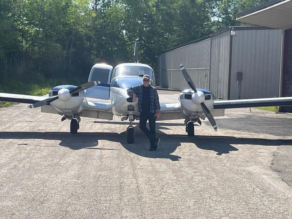 Treat Williams standing in front of plane
