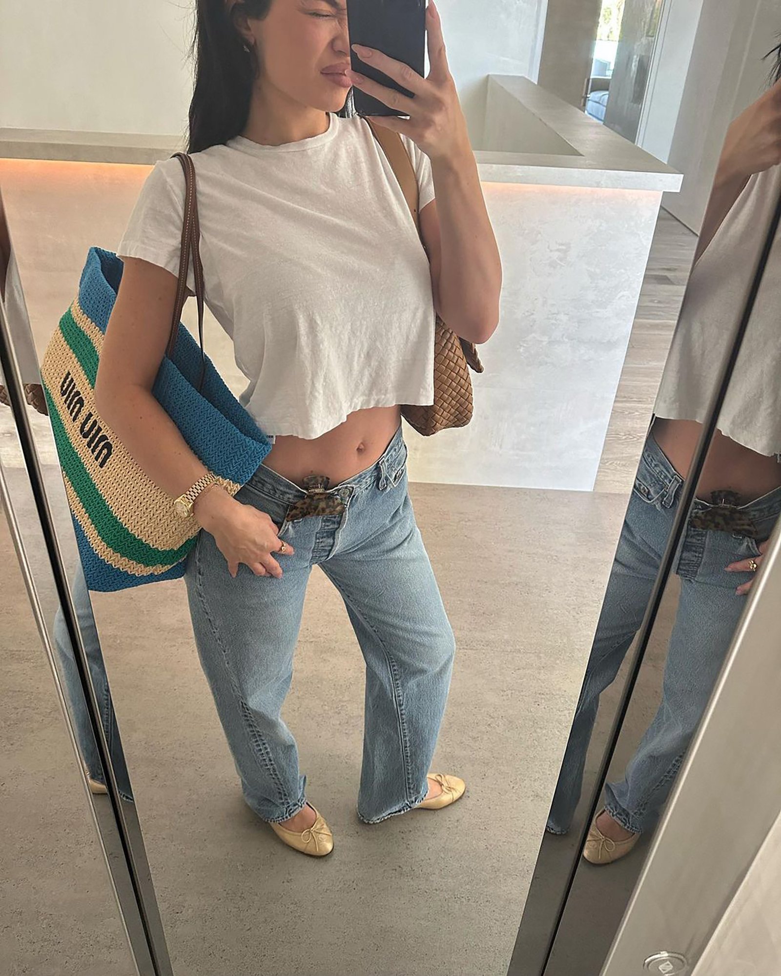 A mirror selfie of Kylie Jenner in a white T-shirt and jeans.