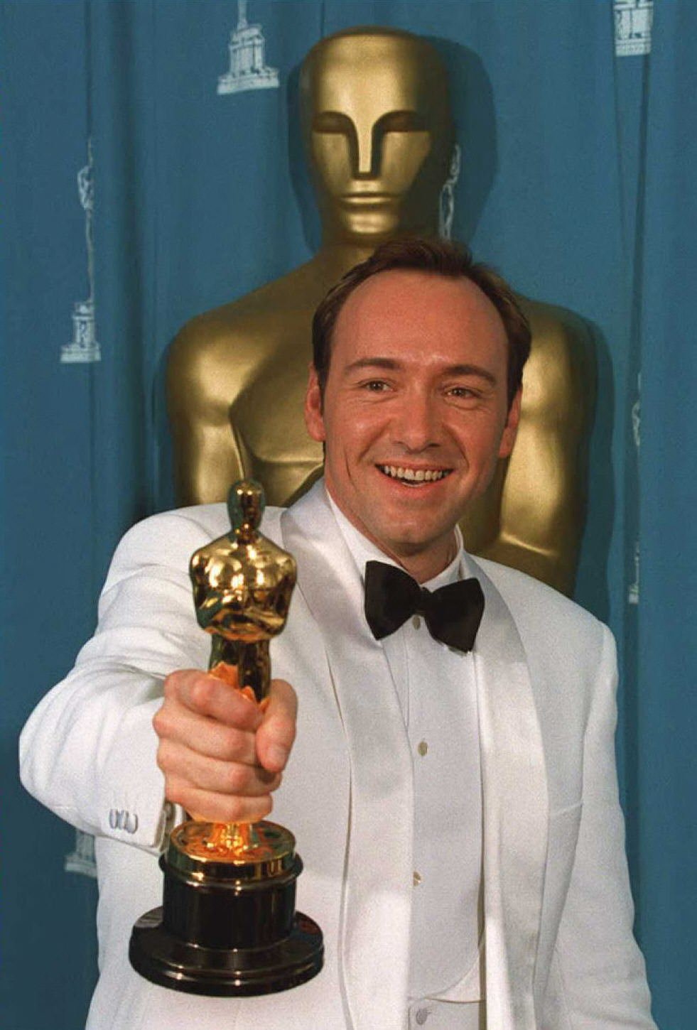 Kevin Spacey holding up his Oscar after winning the award.