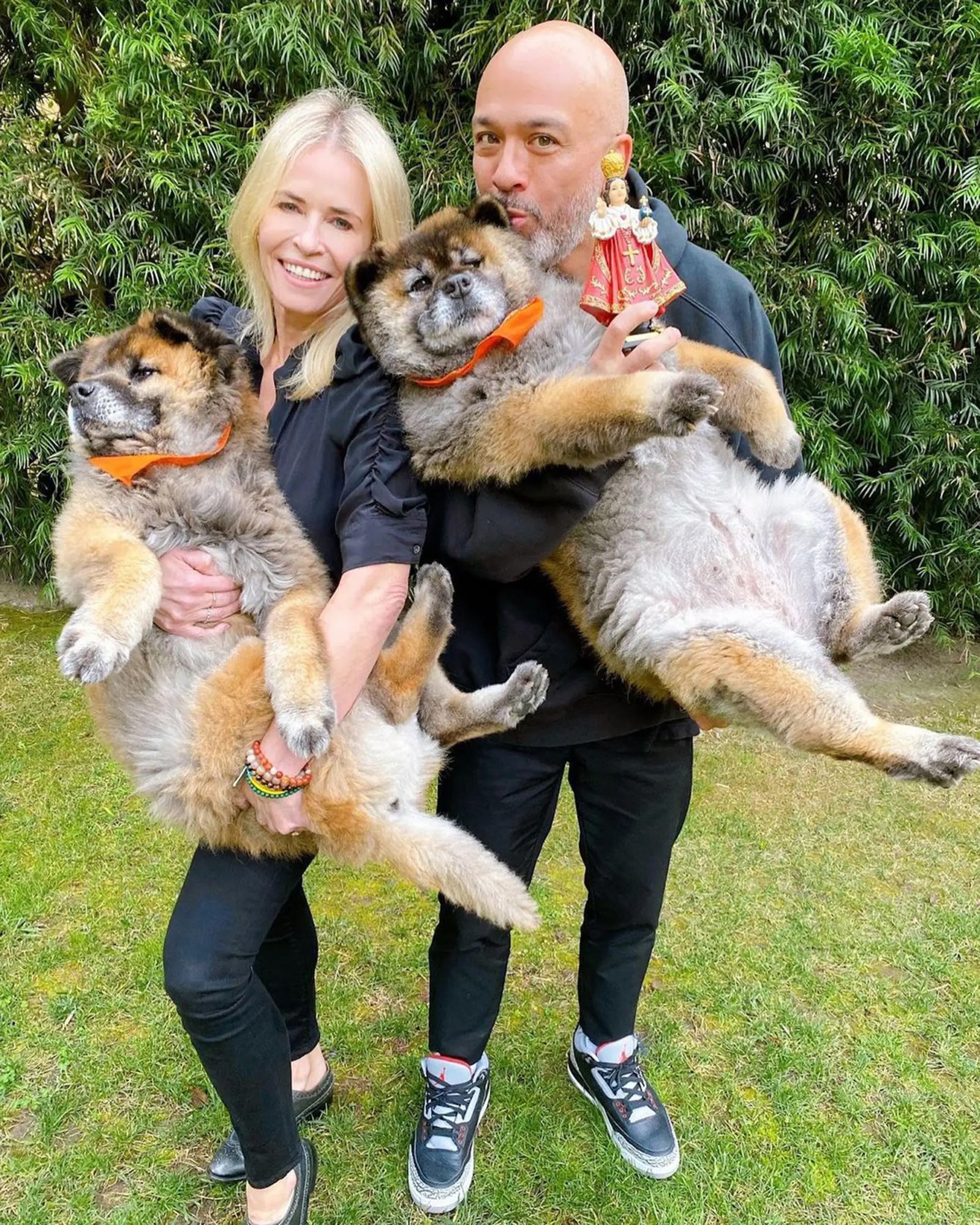 Jo Koy and Chelsea Handler holding dogs.