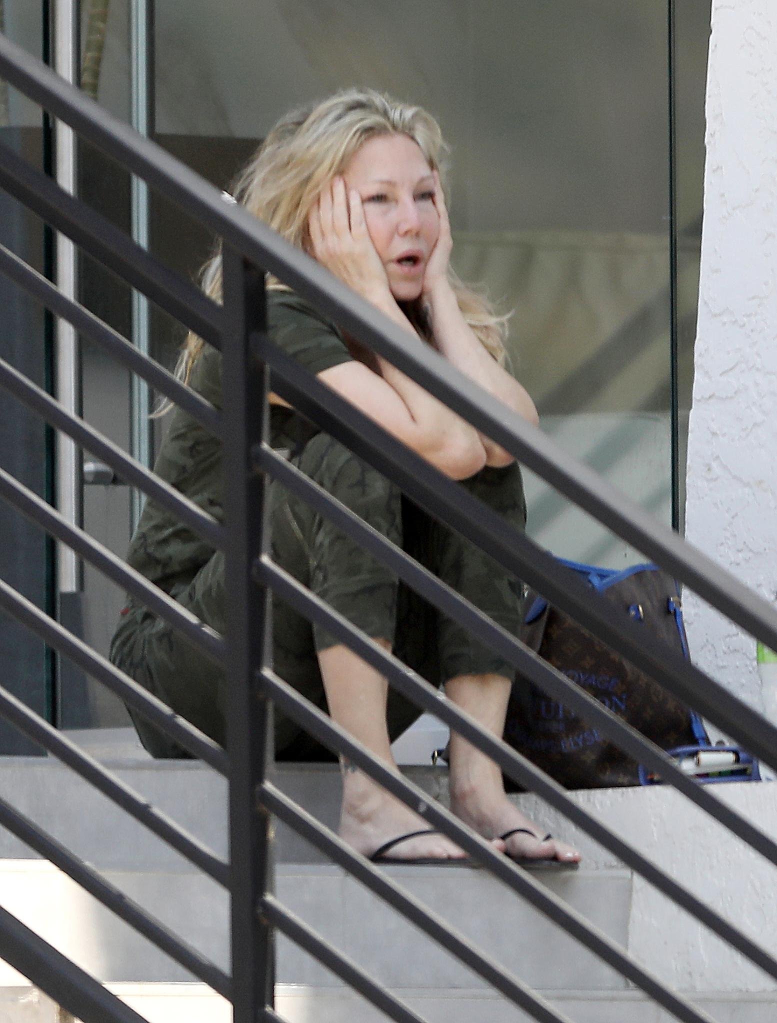 Heather Locklear sitting on steps outside an office building.