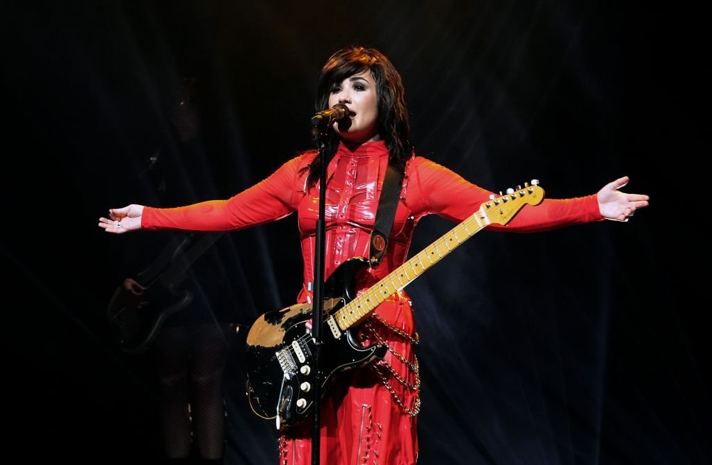 Demi Lovato performing with an electric guitar.