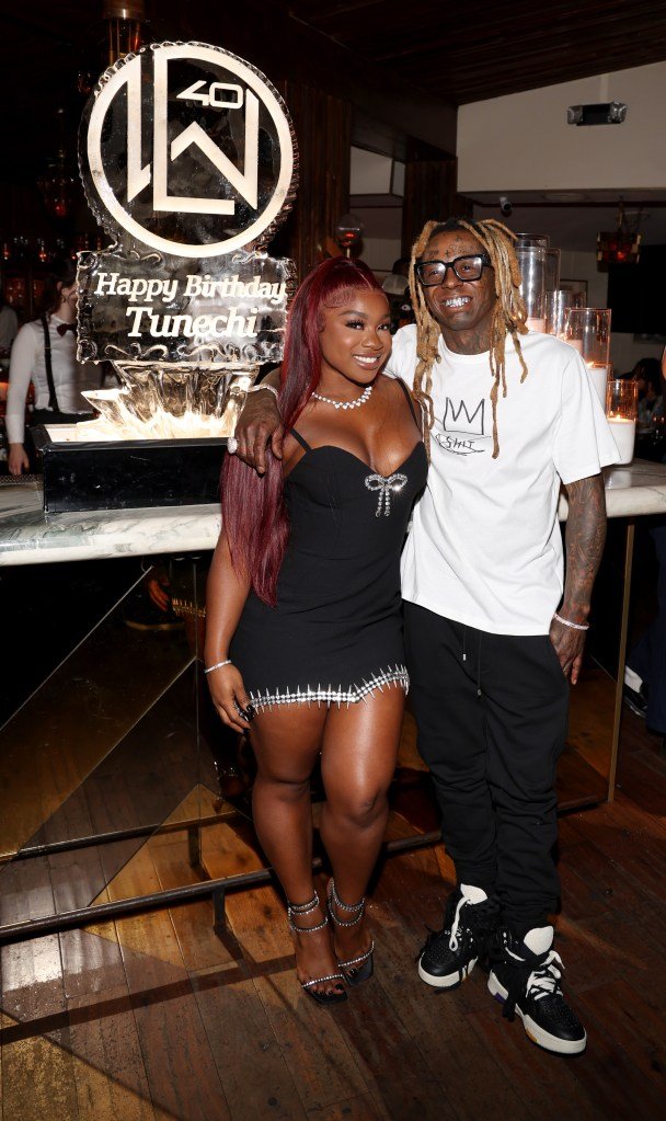 Reginae Carter and Lil Wayne smiling and posing at party.